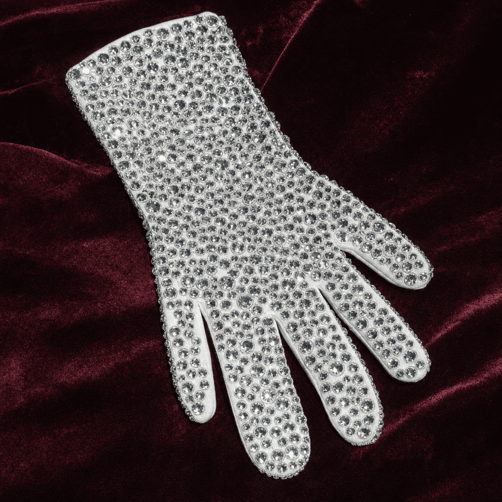A single white cotton dress glove covered in clear rhinestones, photographed on dark velvet — the right-hand glove that became the most-copied piece of Michael Jackson's Motown 25 stage outfit.